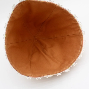Détail de la doublure en coton orange et du bord en dentelle blanche du chapeau fleuri