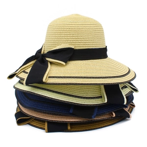 Close-up of wide-brim straw hats in various colors with elegant black ribbon bows