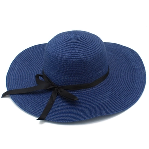 Navy blue straw sun hat with large brim and black ribbon bow for summer beach