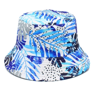 Outdoor bucket hat with blue tropical leaf prints and polka dots on a white background