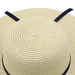 Close-up of fine wheat straw weaving texture and black ribbon on a wide brim sun hat