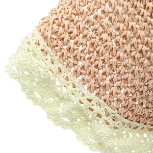 Dettaglio di un cappello di paglia con pizzo beige all'uncinetto e motivi floreali