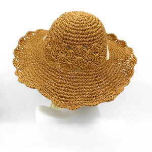 Detail of hollow crochet weave pattern on caramel brown straw hat with lace strap