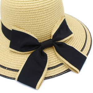Detail of elegant straw sun hat featuring a wide black satin bow and tight weave texture