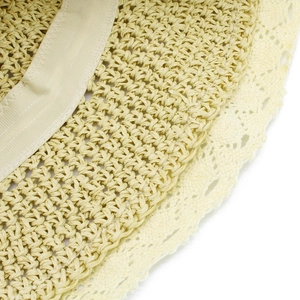 Dettaglio del cappello di paglia con trama intrecciata, bordo in pizzo bianco e cuciture