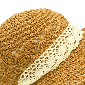 Close-up of handmade straw hat featuring intricate hollow crochet patterns and lace ribbon