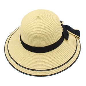Close-up of beige woven straw hat with elegant black ribbon and decorative bow detail