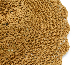 Detail of caramel straw hat showing handmade hollow weave and wavy scalloped edge