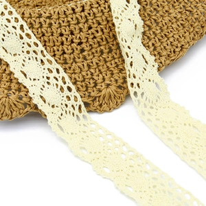 Close-up of handmade crochet lace detailing with hollow patterns on a foldable straw hat