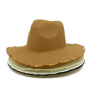 Close-up of stacked raffia straw sun hats showing fine woven textures and raw fringe edges