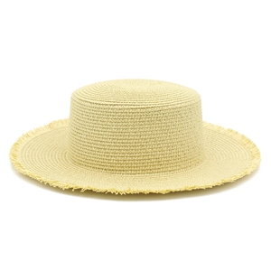 Dettaglio della trama del cappello di paglia con bordi sfrangiati e corona piatta alla moda