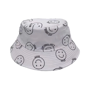 Détail d'un chapeau bob blanc en coton avec des motifs smileys noirs et graphiques