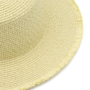 Dettaglio dei bordi sfrangiati di un cappello da sole in paglia intrecciata gialla