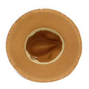 Top down detail of woven straw sun hat showing fringed edge texture and khaki fiber