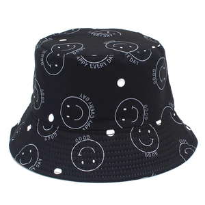 Détail d'un bob noir avec pois blancs, visages souriants et coutures de bord précises