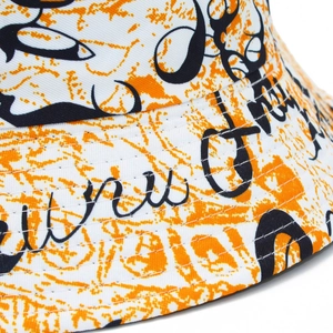 Détail du chapeau bob avec imprimé graffiti, textures oranges et finitions des coutures
