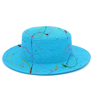 Macro detail of a bright blue woven straw boater hat with colorful artistic paint splatters