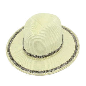 Detailed texture of cream Panama hat with decorative pearls and metallic studs