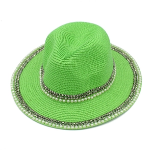 Detail of neon green straw hat with rows of white pearls and silver metal rivets