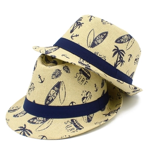 Nahaufnahme von cremefarbenen Strohhüten mit marineblauem Surfdruck und passenden Bändern