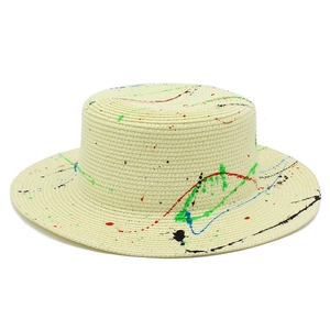 Detailed macro view of beige boater hat showing woven straw texture and vibrant paint splatters