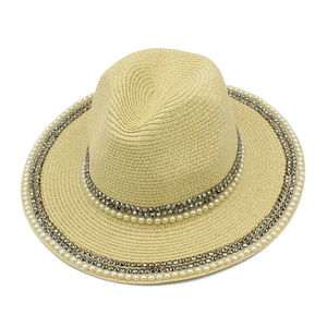 Close-up of straw sun hat with detailed white pearl and dark grey metal stud embellishments