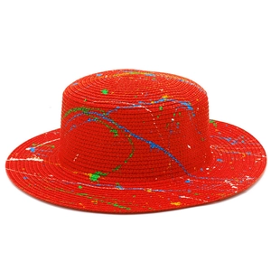 Detailed macro view of red straw Panama hat featuring colorful artistic paint splatters