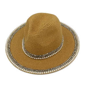 Detailed texture of straw Panama hat featuring white pearls and silver metal studs