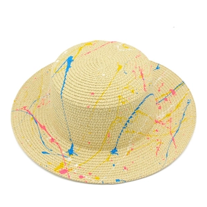 Close-up of woven straw sun hat featuring artistic blue and yellow paint splatter details