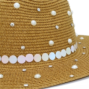 Detail of hand-woven straw hat with elegant pearls, rhinestones and iridescent sequins