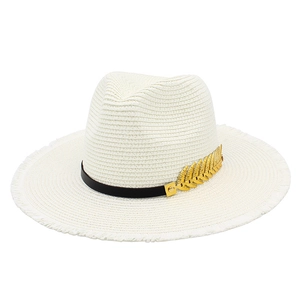 Detailed view of white woven straw hat featuring a golden feather metal accessory
