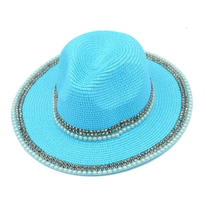 Detail of blue straw hat featuring woven texture, pearl beads, and studded accents
