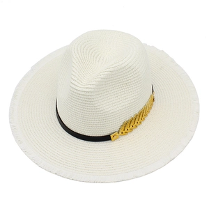 Detail of white straw jazz hat with raw fringe edges and gold leaf metal ornament