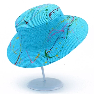Detail of blue straw sun hat showing artistic multicolor paint splatter splash effects