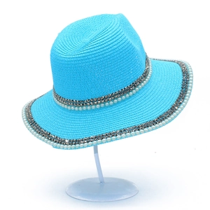 Bright blue wide-brim straw sun hat with pearls and rhinestone bands on a white stand