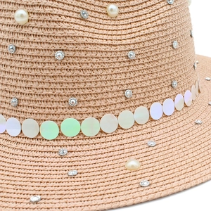 Macro detail of straw hat featuring pearl decorations, rhinestones, and iridescent sequins