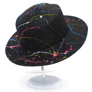 Detailed texture of black wide brim straw hat with vibrant colorful paint splatter design