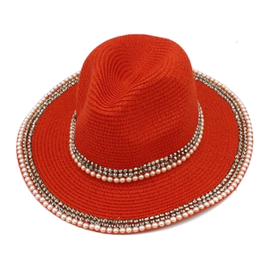 Detail of orange straw fedora hat with white pearl and silver stud embellishments