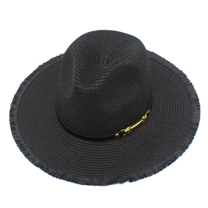 Détail du chapeau de soleil en paille noire avec bord effiloché et boucle dorée chic