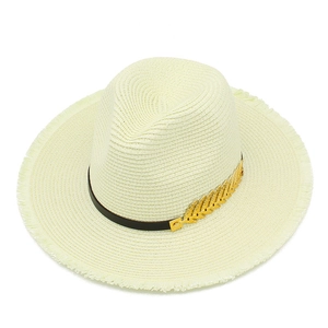 Detail of fedora straw hat with frayed edges and gold leaf ornament on leather band