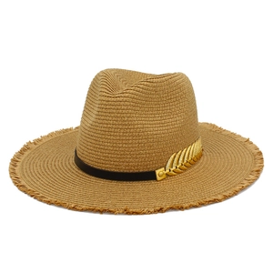 Detail of woven straw fedora with raw edges and a gold leaf metal accessory on band