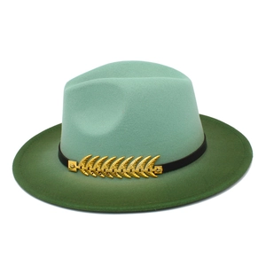 Detail of green gradient fedora hat featuring a gold feather buckle and black band
