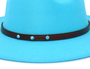 Macro detail of a bright blue felt fedora featuring a brown leather band and turquoise studs