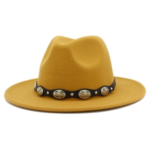 Detalle de sombrero fedora de fieltro amarillo con banda de cuero y tachuelas