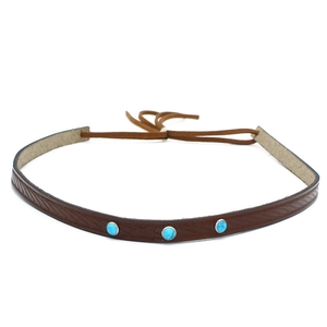 Gros plan sur bande en cuir marron avec motifs feuilles et pierres turquoise bleues