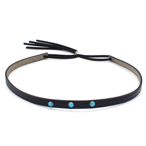 Detail of bohemian black leather belt with turquoise stones and fringe tassel
