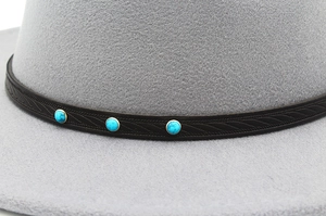 Detail of light gray felt fedora with black woven leather band and blue stone accents