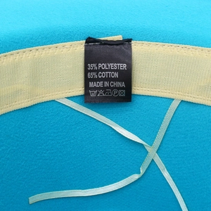 Internal detail of a blue wool fedora hat featuring a beige woven sweatband and material tag