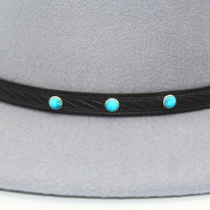 Close-up of vintage embossed leather band with turquoise beads on a gray wool fedora hat