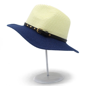 Close-up of two-tone straw hat featuring black leather band and golden metal rivets
